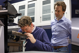 two people looking at a microscope 